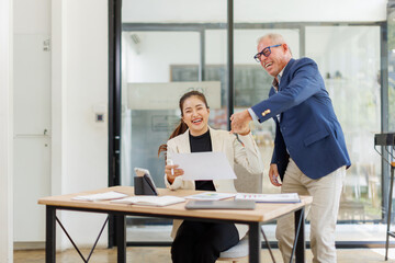 Obraz premium Two business people, a business man and a business woman, engage in a discussion as they read a financial report together. asian business professionals working together in a modern finance company.