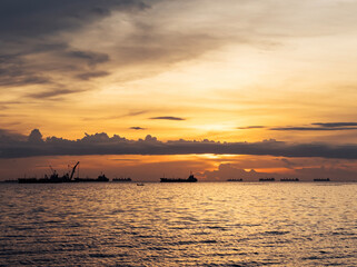 Naklejka premium Stunning sunset over calm waters with distant ships at sea near the coastline