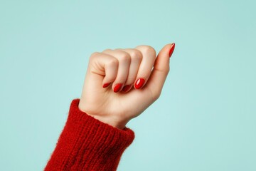 Woman's hand in red sweater against a light blue background