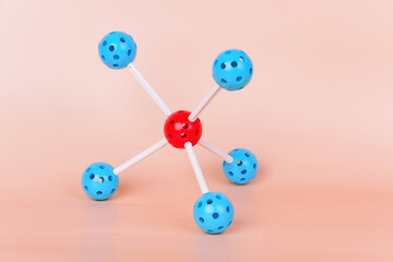 Obraz premium Molecular model with a central red sphere and blue spheres connected by white rods, representing the structure of a molecule