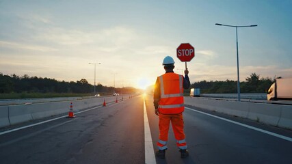 Highway worker holding stop sign on road at sunset - Powered by Adobe