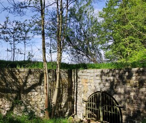 Natursteinmauer mit Metalltor an Wasserlauf