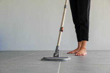 Woman mops the indoor floor, cleaning the front area of her home with a mop and rag. Housewife dedicated to maintaining cleanliness. Represents professional housekeeping and house maintenance concepts