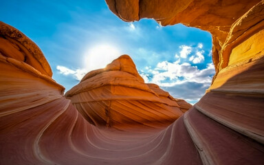 A dramatic photograph of a natural sandstone wave formation captured from a low angle, looking upward