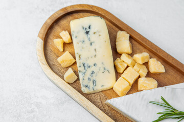 Cheese platter featuring blue cheese, cheddar, and fresh herbs on a wooden tray