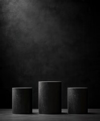 Three dark cylindrical platforms against a textured black backdrop, lit from above