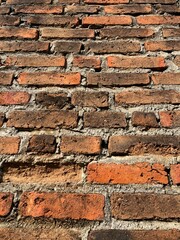 This is a high-resolution photo of a rustic brick wall, showing weathered red and brown bricks with visible textures and natural imperfections. The mortar lines are rough and uneven