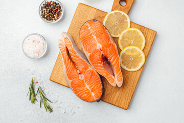 Fresh salmon fillets on a wooden cutting board with lemon slices