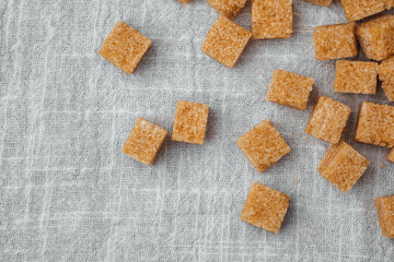 Brown sugar cubes scattered on a linen cloth fabric surface in a kitchen setup
