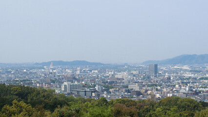 Obraz premium Kyoto, Japan – April 15, 2024: Panoramic view of Kyoto city and surrounding mountains from the summit of Mount Inari, along the path of Fushimi Inari Taisha, one of Japan’s most iconic landmarks.