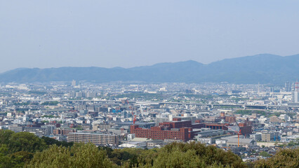 Naklejka premium Kyoto, Japan – April 15, 2024: Panoramic view of Kyoto city and surrounding mountains from the summit of Mount Inari, along the path of Fushimi Inari Taisha, one of Japan’s most iconic landmarks.