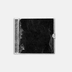 Close-up of a CD case wrapped in torn transparent plastic with a black background insert. Ideal for album artwork mockups, grunge designs, or retro music packaging.
