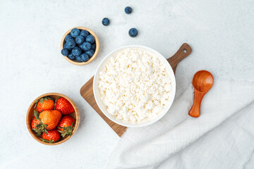 Fototapeta premium Fresh cottage cheese with strawberries and blueberries on a wooden paddle board