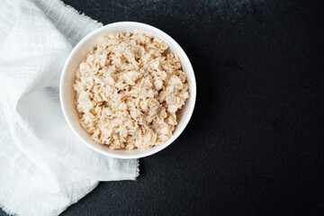 Creamy oatmeal served in a white bowl with a cloth on a dark surface