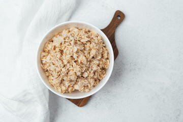Oatmeal served in a bowl on a wooden board in bright kitchen setting