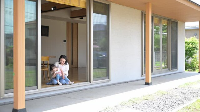 軒先や縁側で抱っこでくつろぐ母親と娘（子供）子育ての幸せのイメージ広角の全身の動画