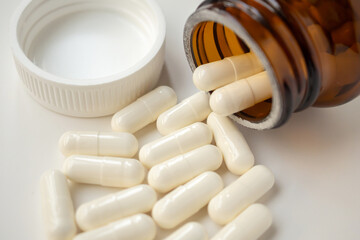 medicine pills capsule spilling out of bottle on white background