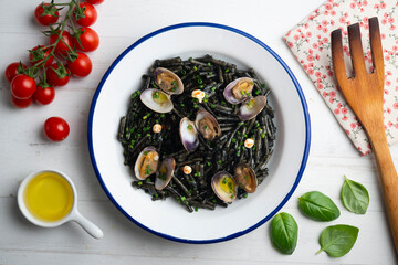 Spanish black fideua. Traditional tapas recipe of noodles with clams and garlic oil. Top view table with christmas decorations.