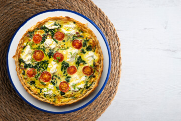 French quiche with spinach, cheese, tomatoes, and diced ham. Top view table with christmas decorations.