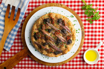 Authentic Italian focaccia with salted anchovies, sun-dried tomatoes, and black olives. Top view table with christmas decorations.