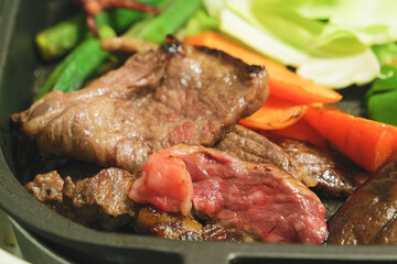 Beef and vegetables are being grilled on a hot plate, the beef looks delicious and tasty!
