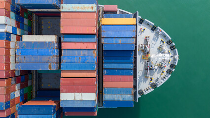 Aerial top view of a large cargo ship fully loaded with colorful shipping containers navigating...