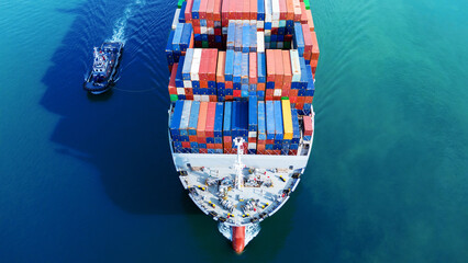 Aerial top view of a large cargo ship fully loaded with colorful shipping containers navigating...