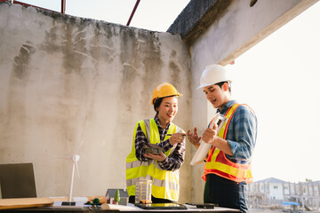 Architects and engineers collaborate at a desk with blueprints and solar panels, planning sustainable energy solutions for eco-friendly construction projects.