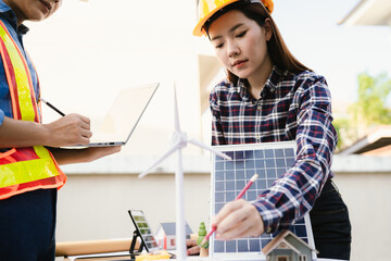 Architects and engineers collaborate at a desk with blueprints and solar panels, planning...