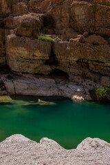 Oman, Middle East, 03-25-2025: Wadi Shab, a narrow canyon home to crystal clear water pools and secret waterfall inside a cave, flowing from the east of the Hajar Mountains down into the Gulf of Oman
