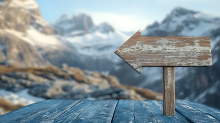 A wooden arrow sign pointing to the left on an old blue wooden table with blurry snow-capped mountains in the background