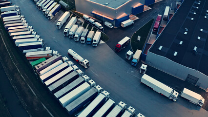Aerial view of a busy parking lot filled with numerous trucks and cargo containers, illustrating a bustling transportation hub. © wkproduction