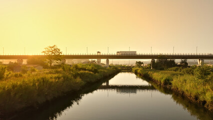 Fototapeta premium Aerial view of a train crossing a bridge over a river, symbolizing connectivity and efficient cargo transportation.