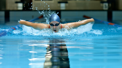 Athlete glides through the pool, demonstrating intense focus and skill in indoor swimming. The dynamic shot captures the swimmer's powerful stroke and determination.