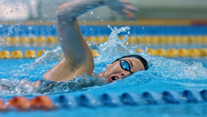 Athlete glides through water, demonstrating skill and speed in an indoor pool. The dynamic shot captures the intensity and focus of competitive swimming.