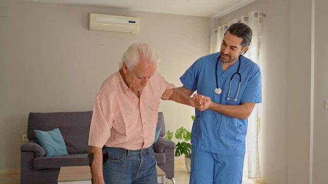 video of Senior man using crutches practices walking with the help of his physiotherapist at home