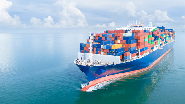 Aerial front view of a large cargo ship fully loaded with colorful shipping containers navigating through calm ocean water. Ideal for logistics, transport, and global trade concepts. - Powered by Adobe