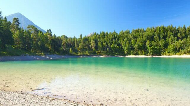 Calm forest lake Urisee near Reutte in the Tyrolean Alps, clear blue water and tranquil shoreline in remote nature setting
