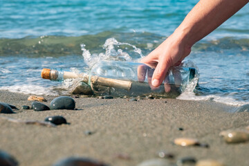 Bottle with message found on sandy beach during bright sunny day near gentle waves, inviting mystery and curiosity