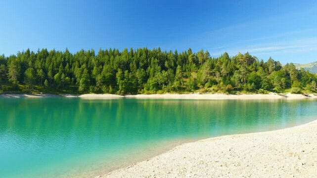 Urisee alpine lake in the Tyrolean mountains with clear water, soft ripples, and tranquil forest scenery under open sky