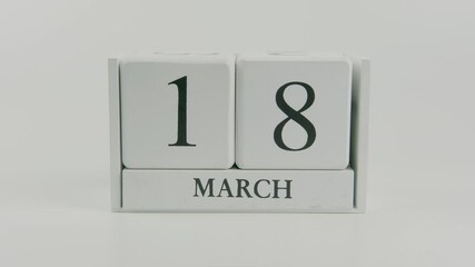 A hand flips a wooden calendar from October 18th to October 19th on a white background, marking the passing of time and the start of a new day