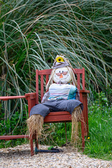 scarecrow gardener sitting on a bench in the garden