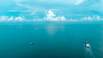 Aerial stern view of a large cargo ship fully loaded with colorful shipping containers navigating through calm ocean water. Ideal for logistics, transport, and global trade concepts.