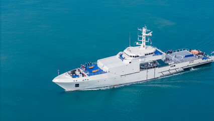 Naklejka premium Aerial view of a modern patrol vessel sailing on calm turquoise sea, equipped with radar, deck equipment, and a helipad. Concept of maritime security, naval operations, and coast guard missions.