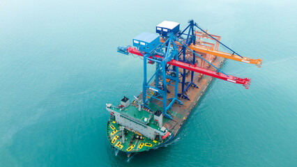 Aerial view of a heavy lift vessel transporting massive port cranes across turquoise waters. Concept of industrial shipping, maritime logistics, port construction, and oversized cargo transportation.
