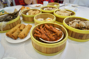 Chicken feet and Yumcha dishes on the table in a Chinese restaurant. Unrecognizable people in the background. Auckland.