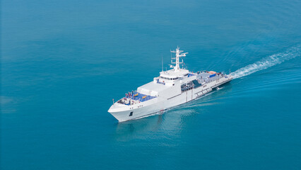 Aerial view of a modern patrol vessel sailing on calm turquoise sea, equipped with radar, deck equipment, and a helipad. Concept of maritime security, naval operations, and coast guard missions.