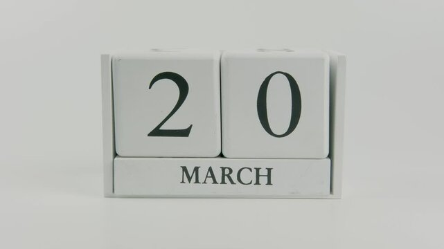 A hand flips a wooden calendar from October 20th to October 21st on a white background, marking the passing of time and the start of a new day