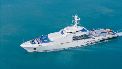 Aerial view of a modern patrol vessel sailing on calm turquoise sea, equipped with radar, deck...