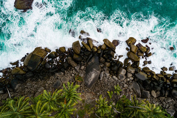Aerial view Top down seashore, Waves crashing on rocks cliff, Beautiful sea surface in sunny day summer background, Amazing seascape top view seacoast at Phuket Thailand